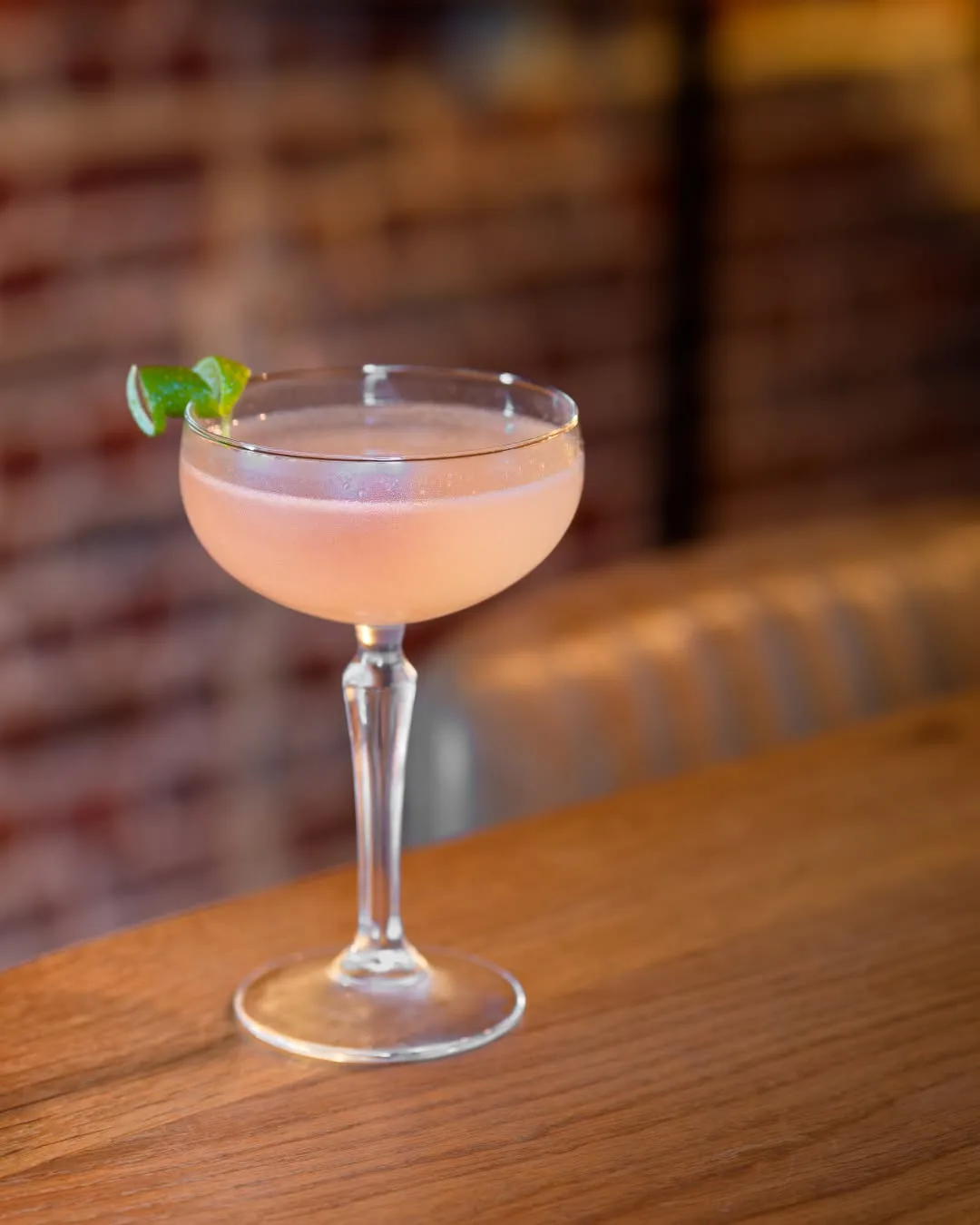 Daiquiri au rhum jamaïcain Hampden servi en coupe avec zeste de citron vert sur le comptoir en bois de The Modern Alchemist à Saint-Gilles, Bruxelles.